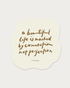 A cream-colored die-cut sticker with an organic wavy shape, featuring the quote &