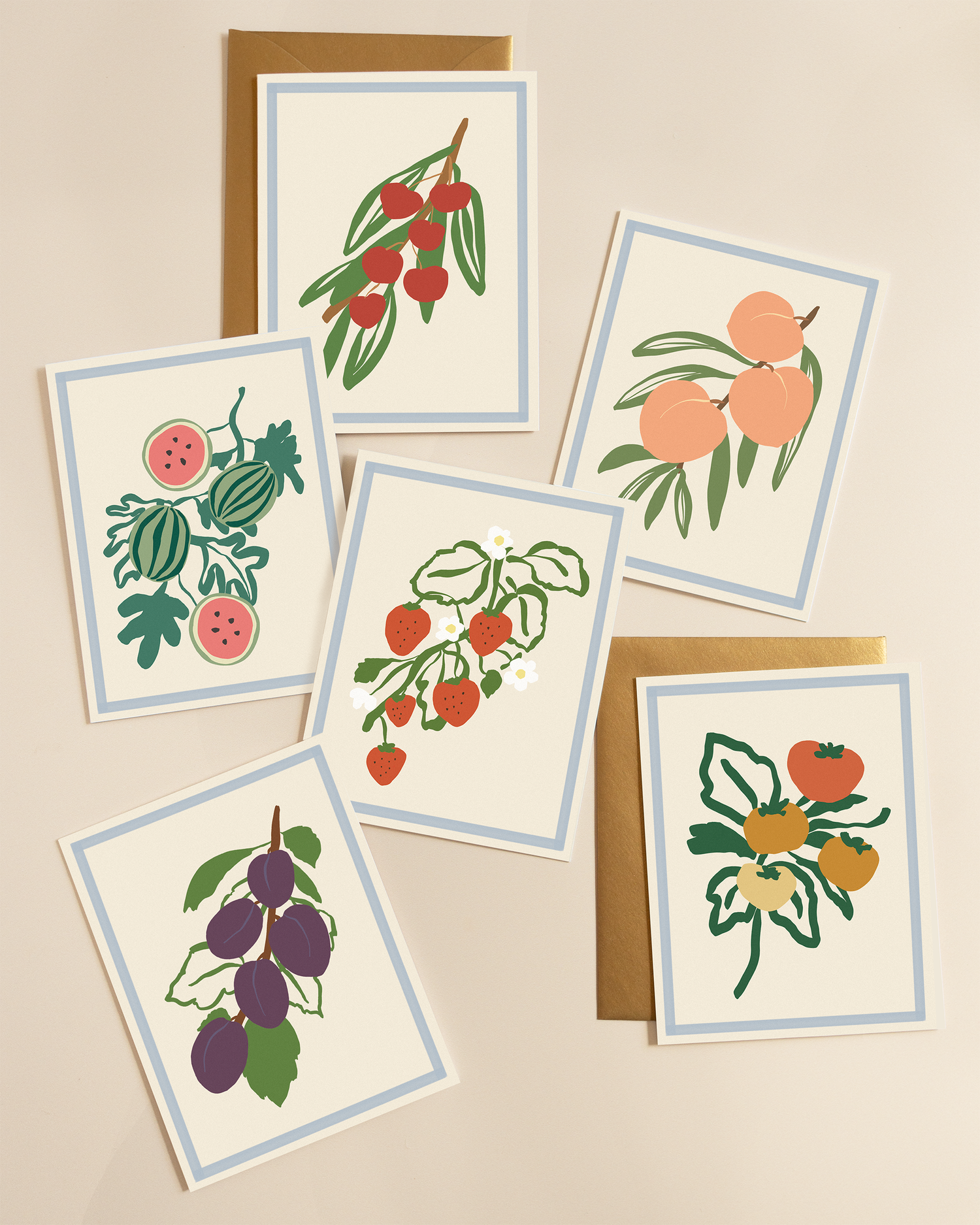 Set of greeting cards with fruit illustrations paired with gold envelopes 