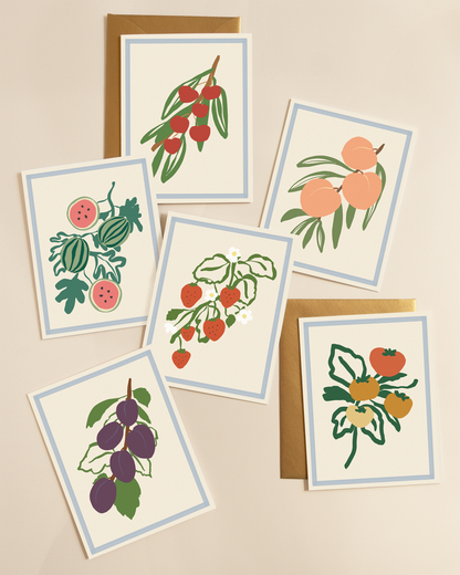 Set of greeting cards with fruit illustrations paired with gold envelopes 